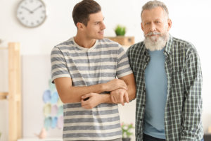 caregiver guiding senior man to walk